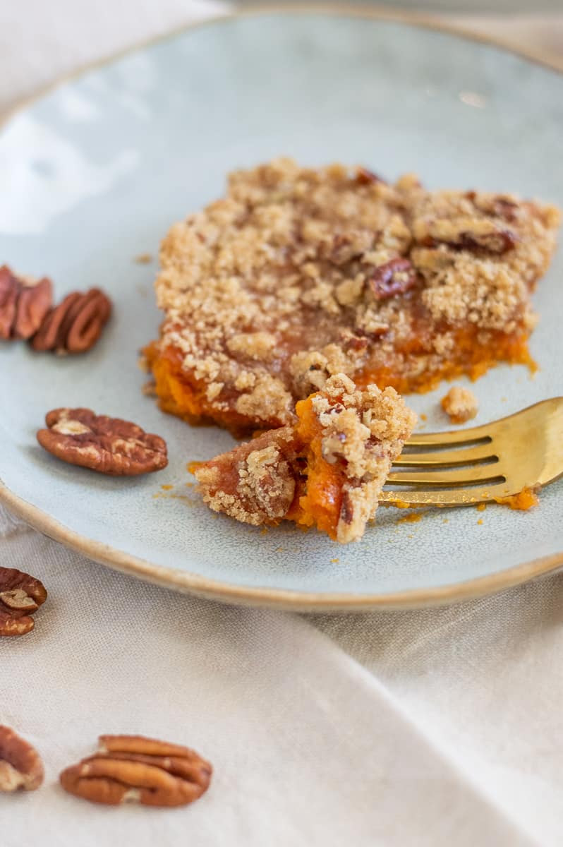 Pecans and sweet potato casserole on a plate with gold fork