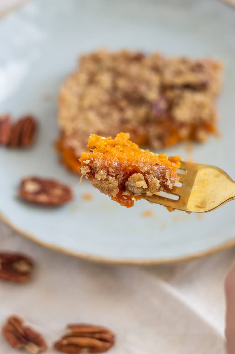 Bite of sweet potato casserole with pecan streusel on a fork