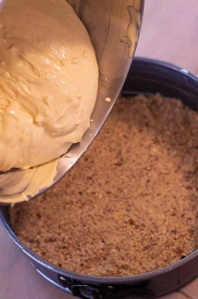 gluten free cheesecake being poured into crust