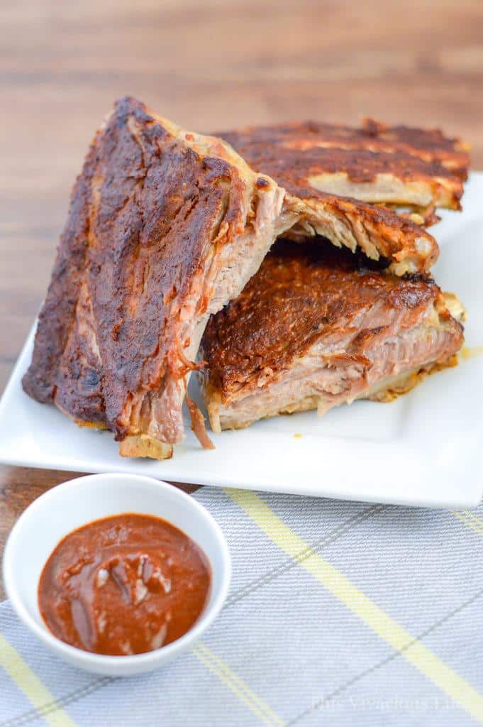 Ribs on a plate with bbq sauce in a cup