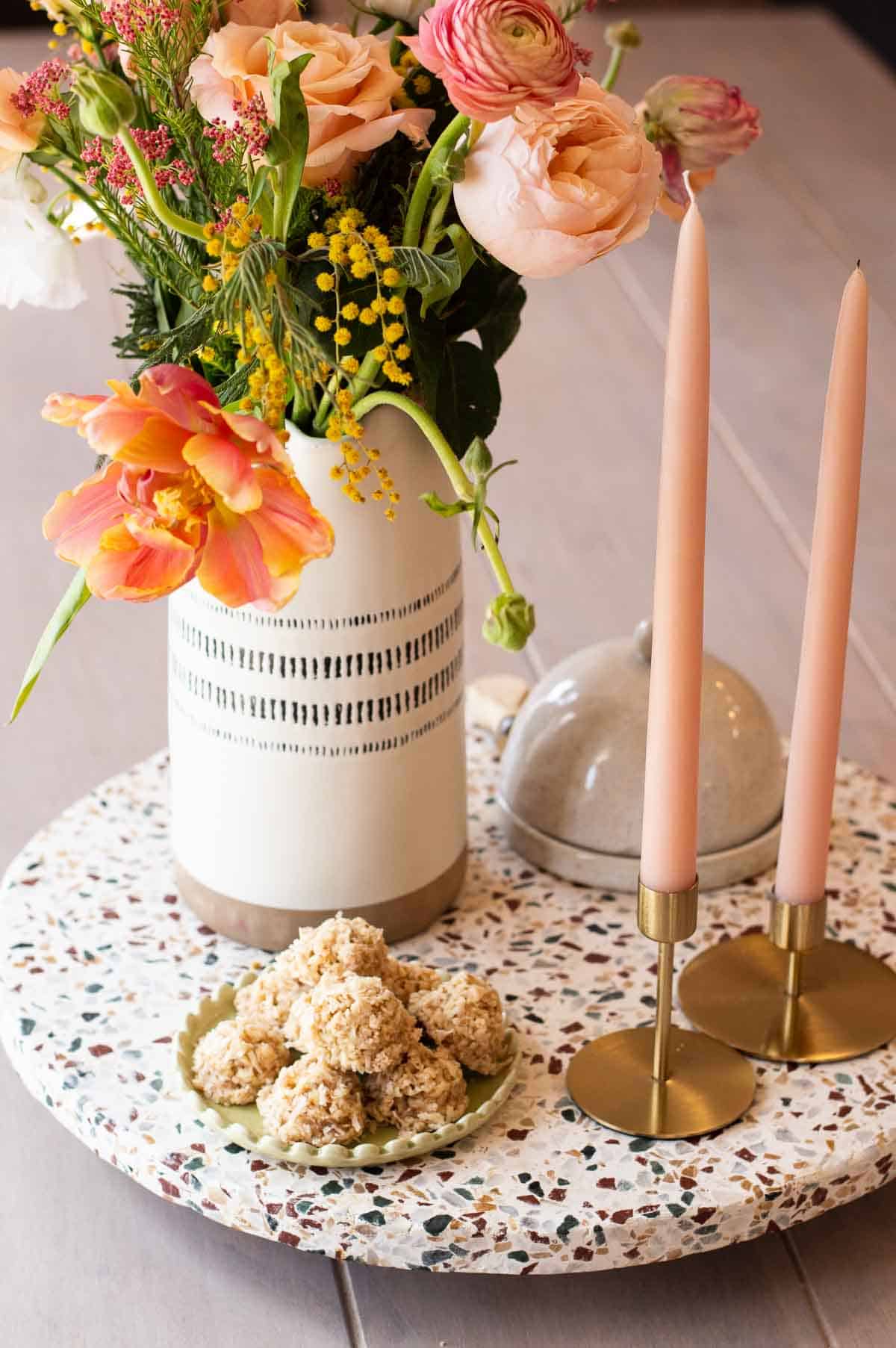 coconut macaroons on a green plate near candles and flowers