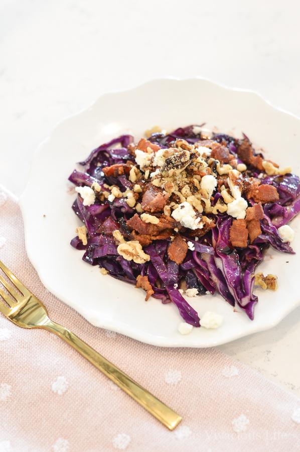 White plate with red cabbage salad topped with bacon