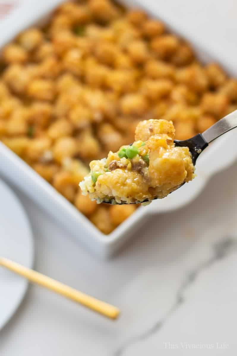 Tater tot casserole on a spoon with main dish behind it