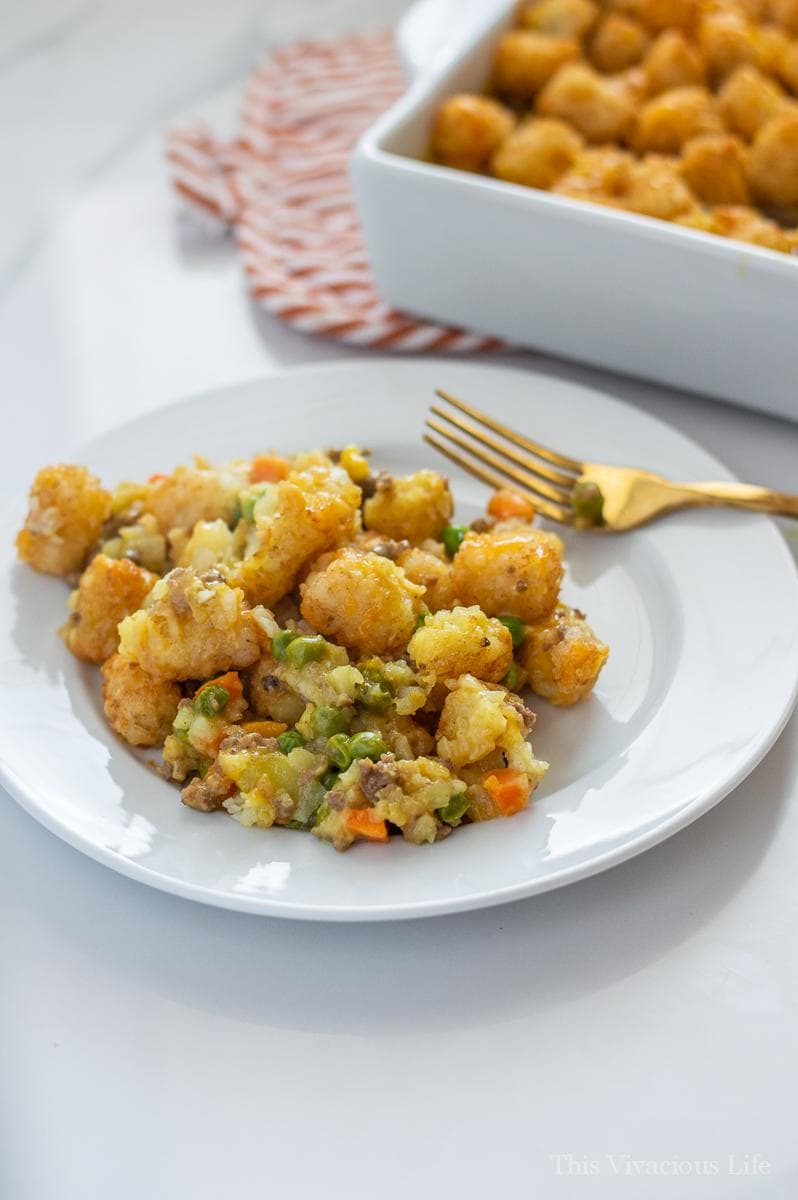 Tater Tot Casserole on a white plate with a gold fork