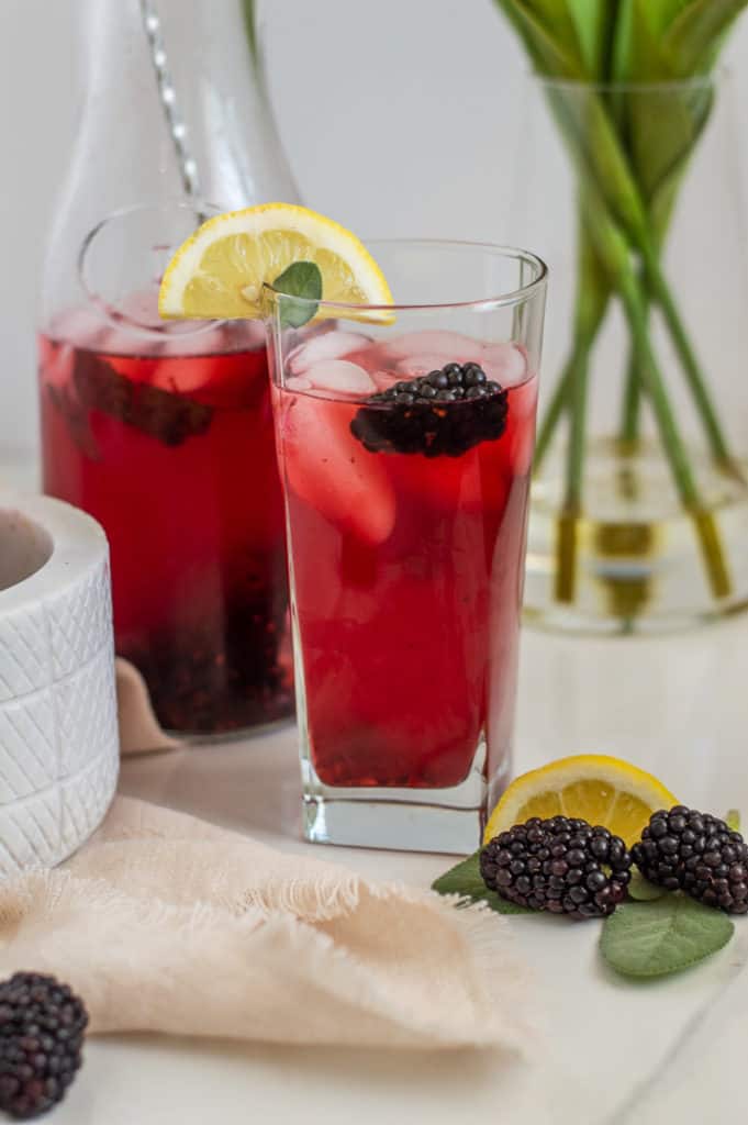 Blackberry lemonade in a glass cup with lemon