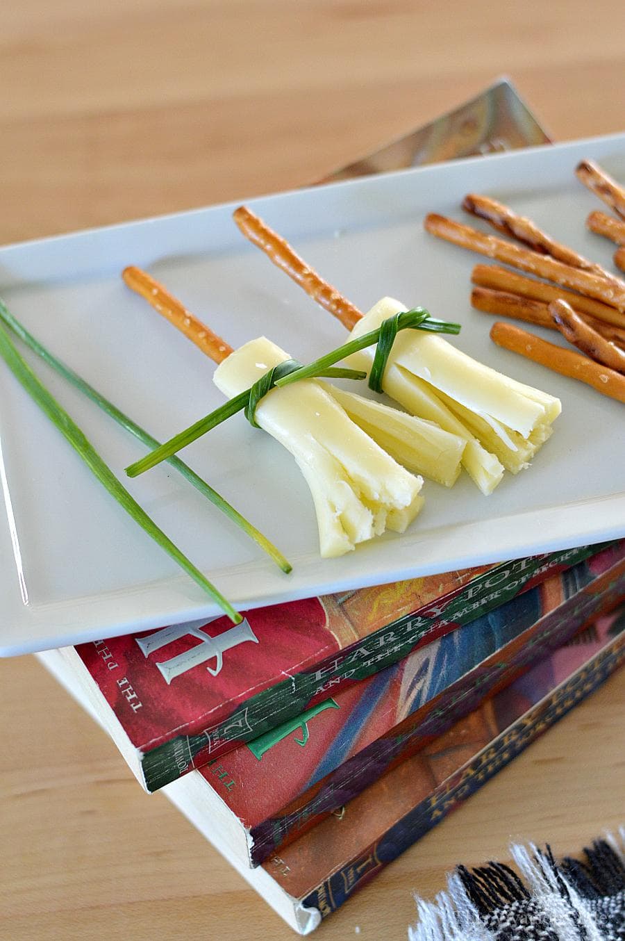 String cheese and pretzel broomsticks on a white plate