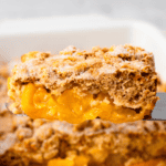 Mom's Gluten Free Peach Cobbler on a serving spoon with crumbly topping and golden fresh peach filling