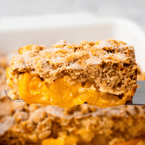 Mom's Gluten Free Peach Cobbler on a serving spoon with crumbly topping and golden fresh peach filling