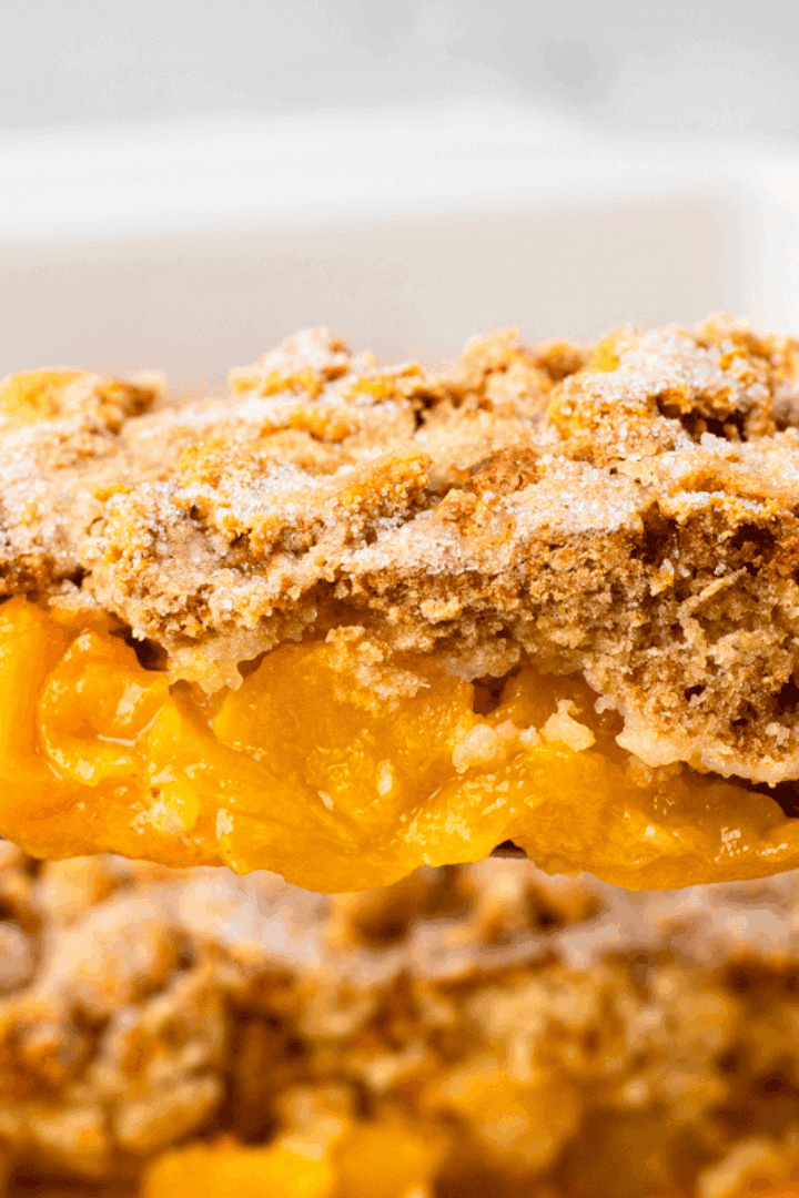 Mom's Gluten Free Peach Cobbler on a serving spoon with crumbly topping and golden fresh peach filling