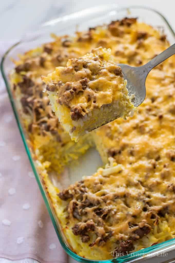 Hashbrown breakfast casserole in a dish with one piece on a spatula