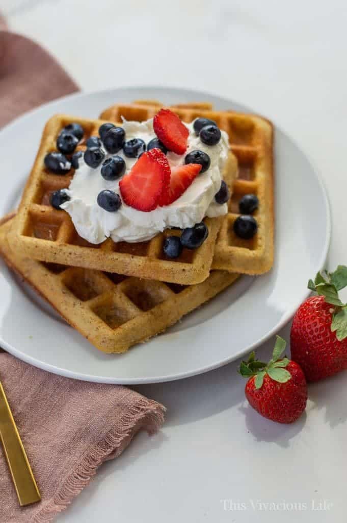 Three square waffles on a white plate with berries