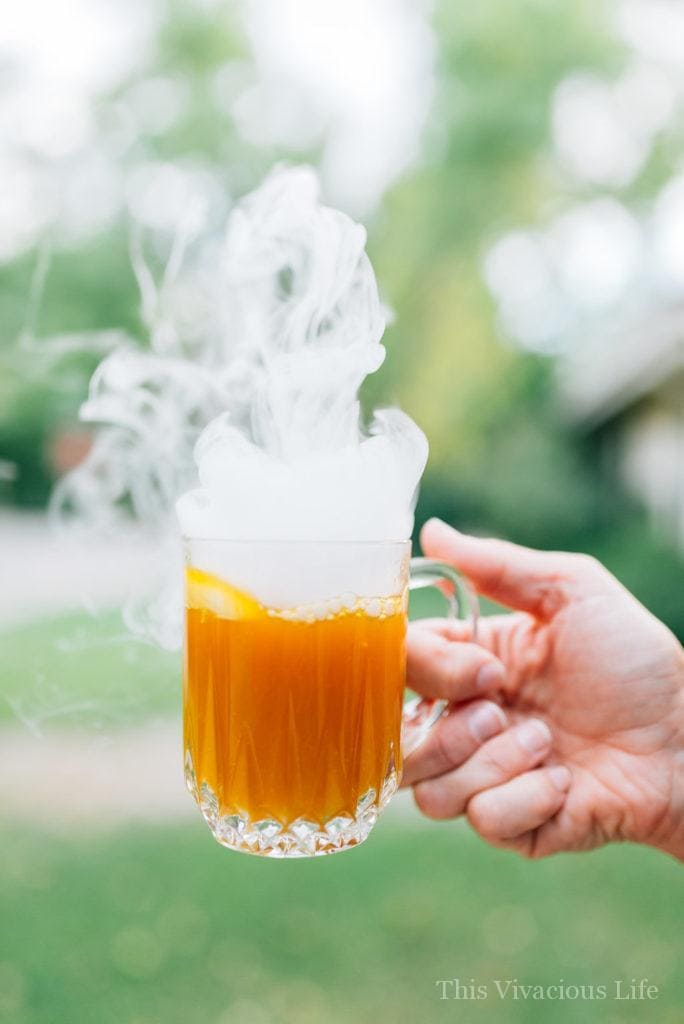 Smoking Halloween pumpkin punch in a glass cup