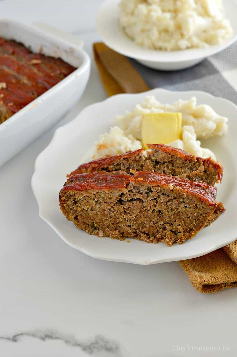 Two slices of meatloaf with ketchup on a white plate