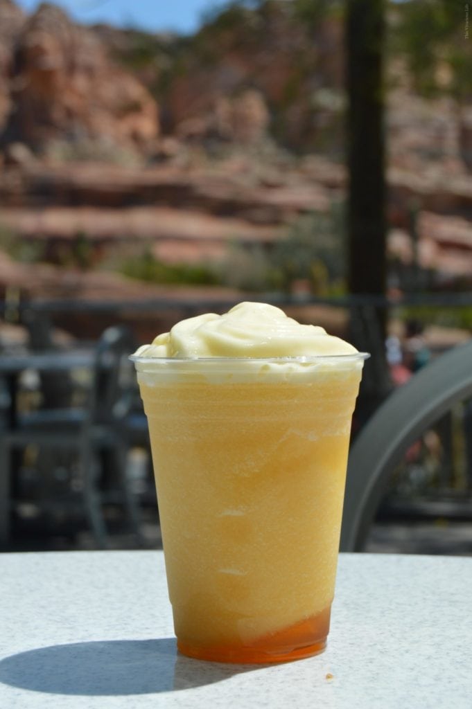 Cup of Disneyland Reds Apple Freeze with mountains in the back