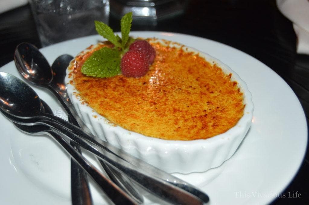 Creme brûlée with raspberries and mint leaves in a white dish