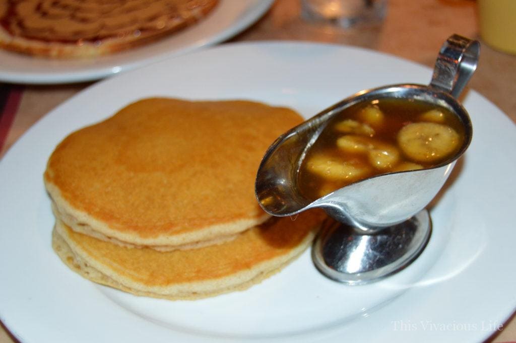 Two gluten-free pancakes and bananas foster on a white plate