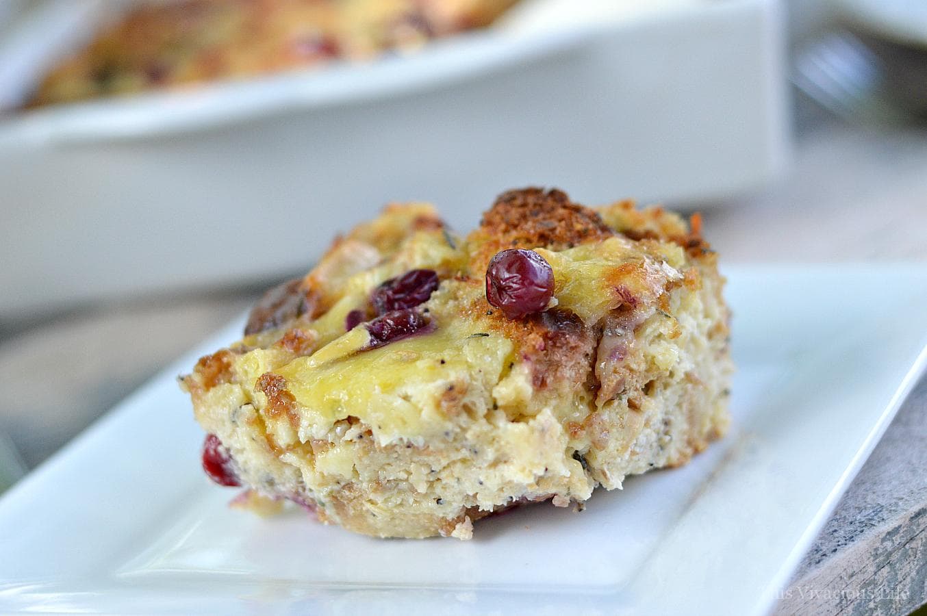 Photo shows a close up of turkey, cranberry and brie bread pudding on a white plate