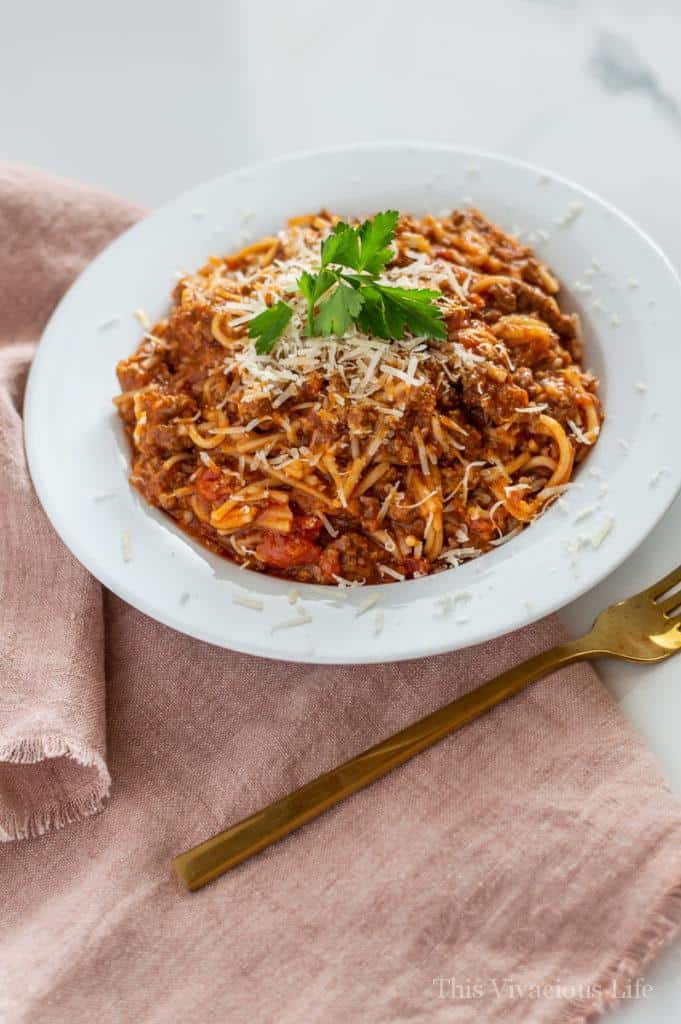 Spaghetti in a white bowl with a light red towel