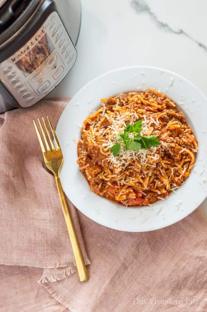 Spaghetti in a white bowl next to an Instant Pot