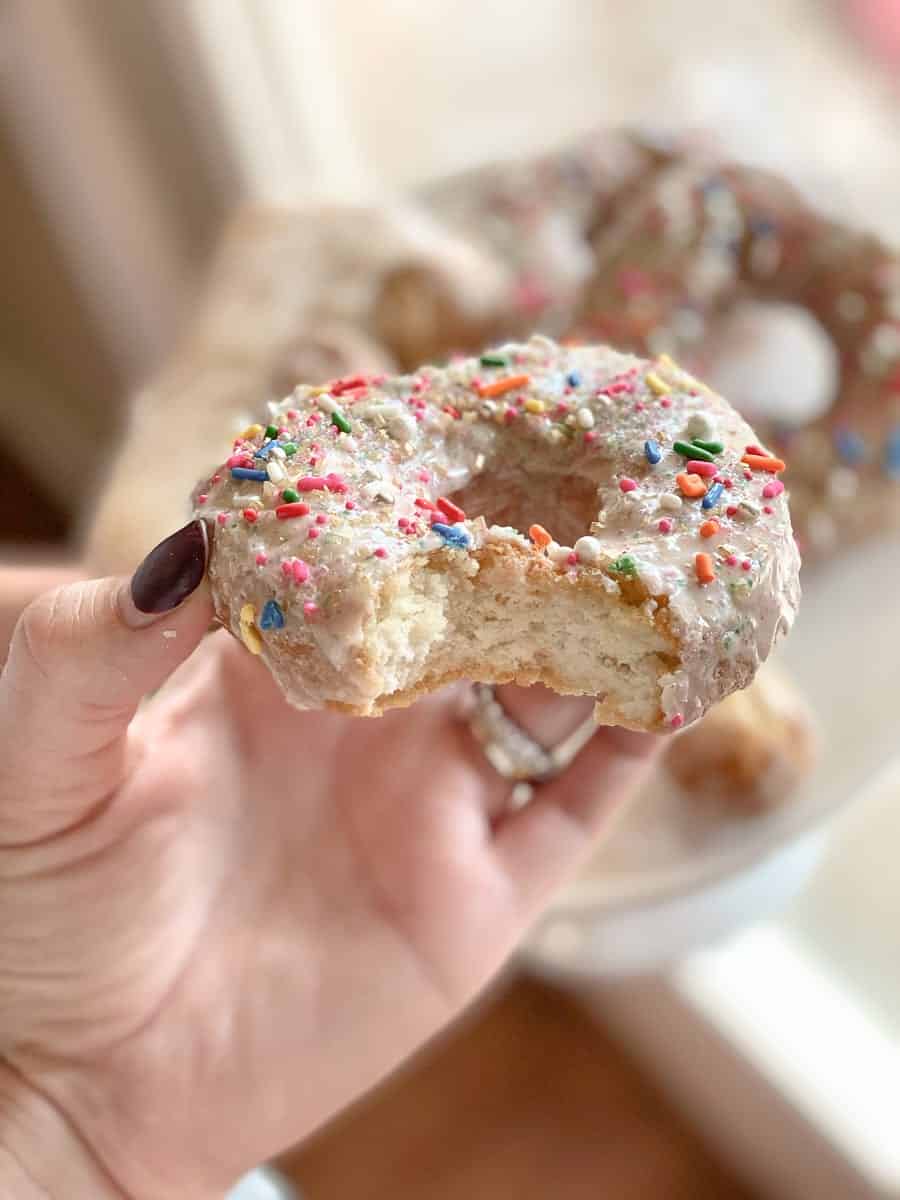 White gluten-free donut with sprinkles in a hand