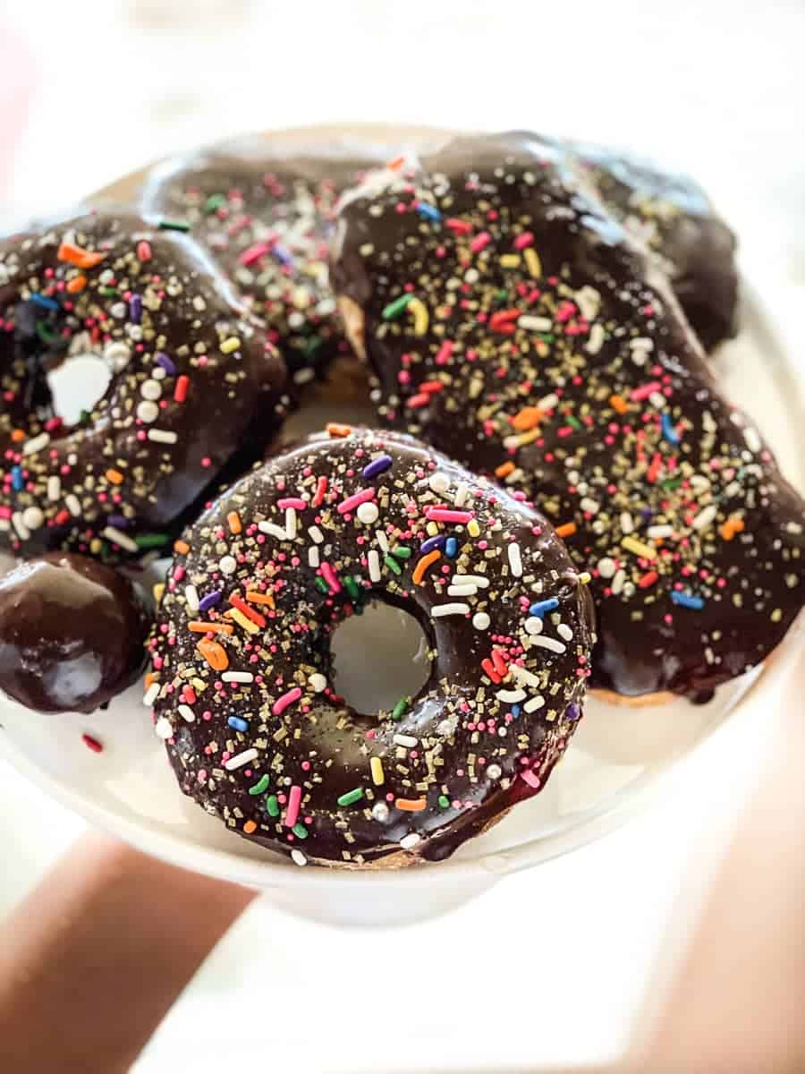 Chocolate glazed sprinkled gluten-free donuts on a cake stand