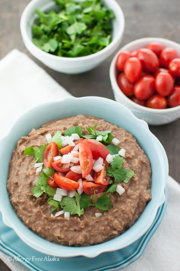 Refried beans in a bowl topped with tomatoes, onions and cilantro