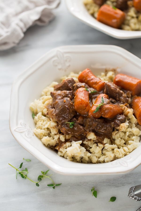 Beef burgundy with carrots over rice in a white bowl