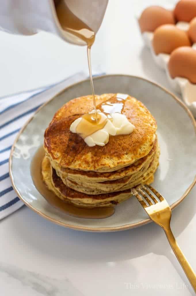 Short stack of pancakes with butter and syrup being drizzled on them