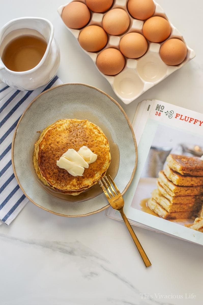 Overhead shot of pancakes on a plate with eggs in a dish