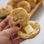 Split biscuit with butter being held