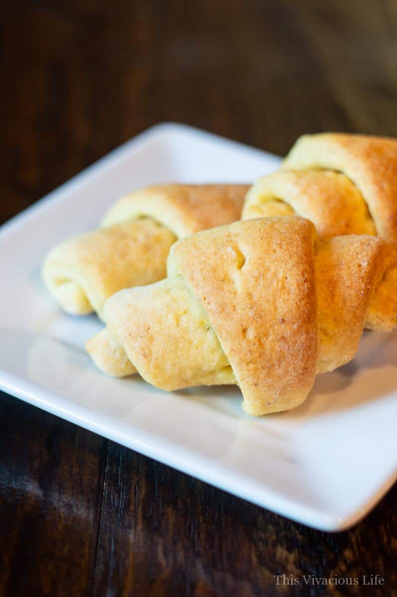 Three gluten-free crescent rolls on a white square plate. 