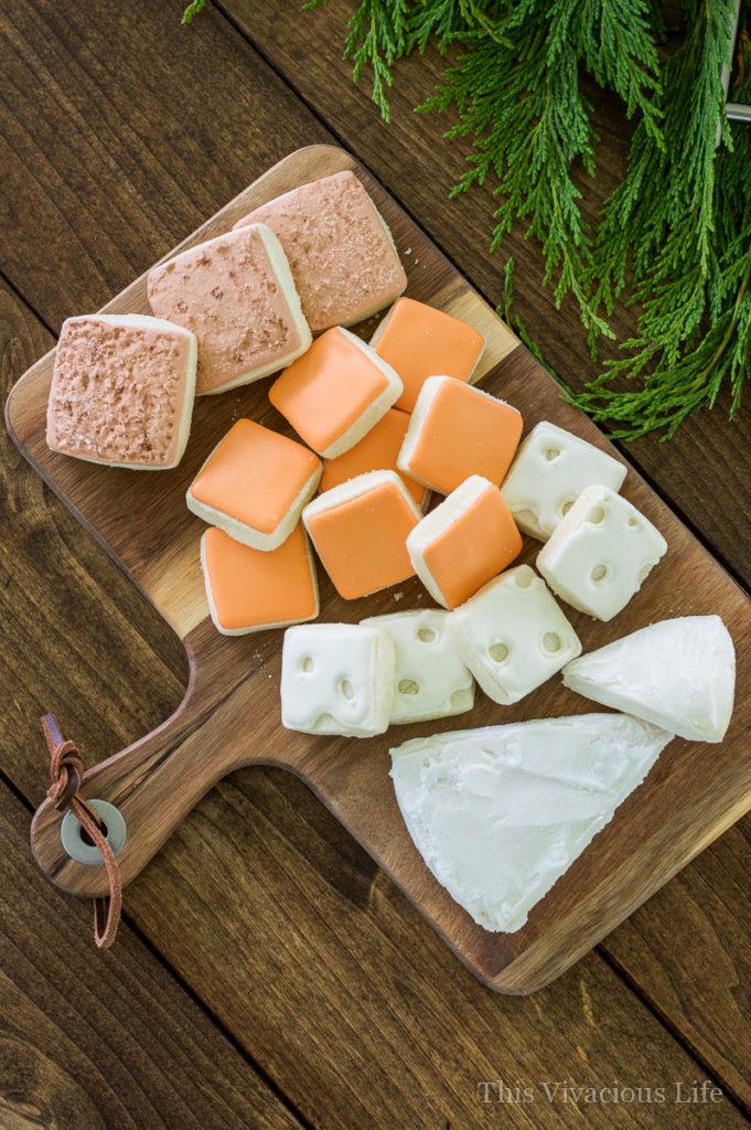 Cheese sugar cookies decorated on a wood cheese board