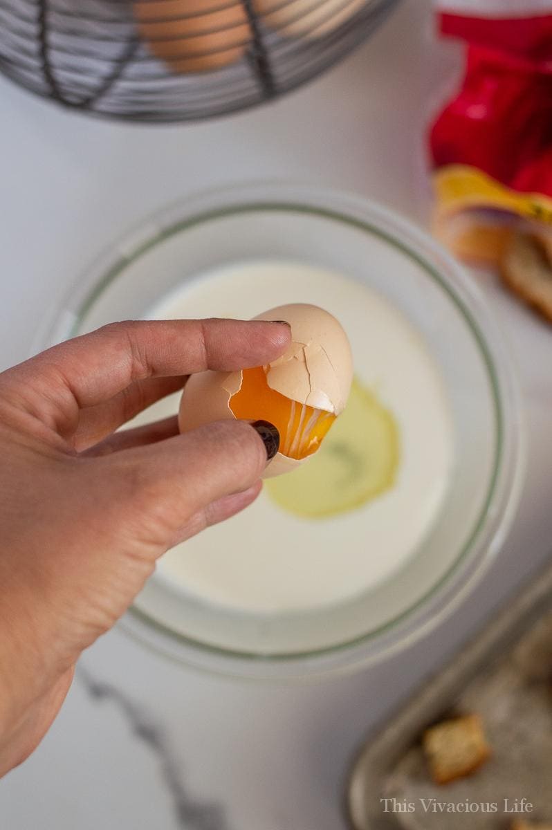 Egg being cracked into a bowl of milk