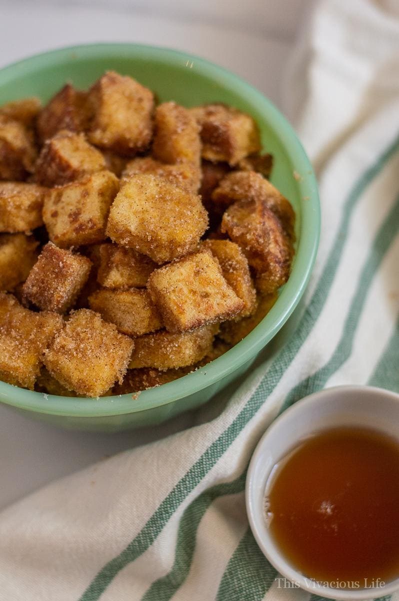 French toast bites in a green bowl with syrup on the side