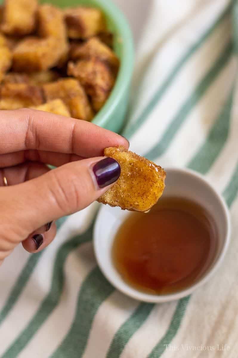 Gluten-Free French Toast Bites French toast bite being dipped in syrup
