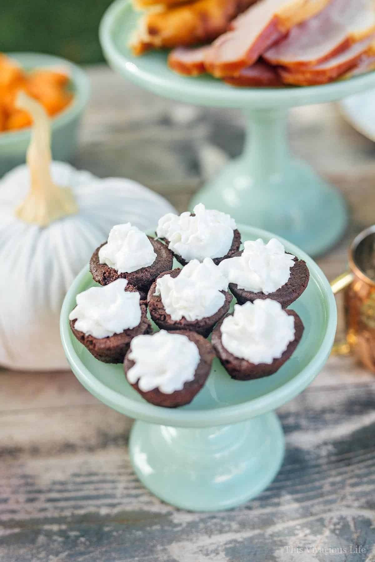 Brownie bites with whipped cream on a jadeite stand