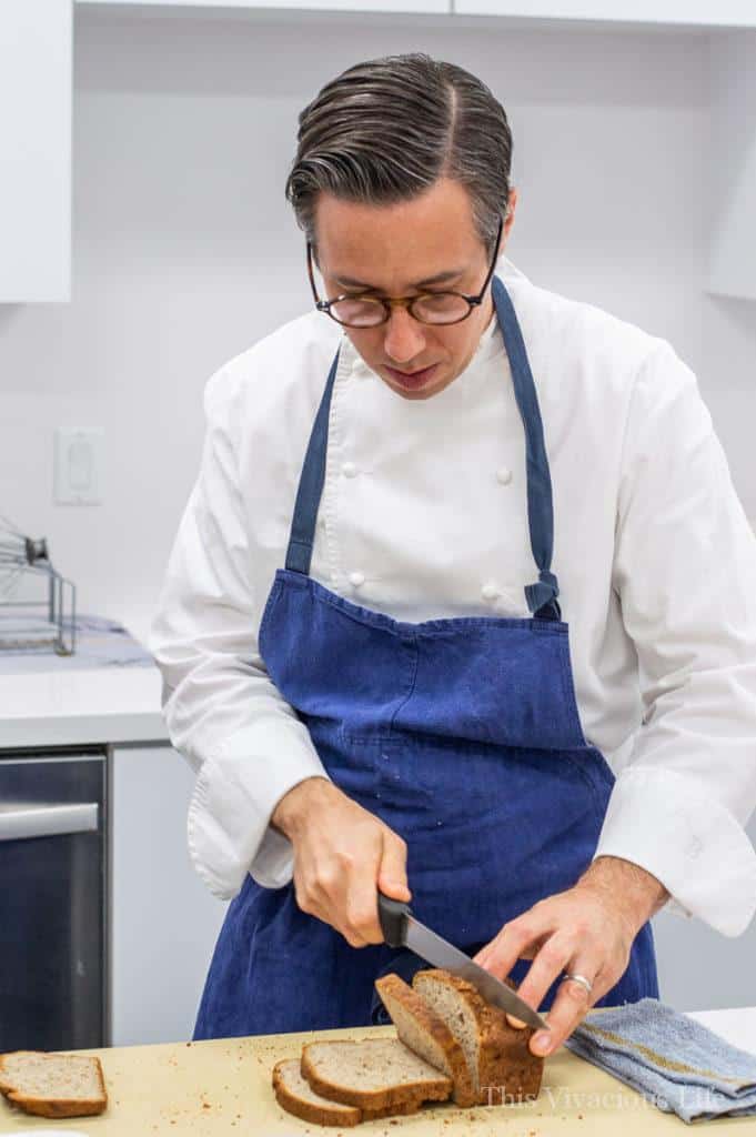 Chef in a blue apron slicing gluten-free bread