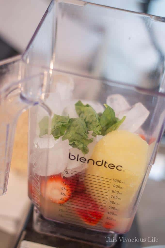 Blender filled with ice, fruit and basil