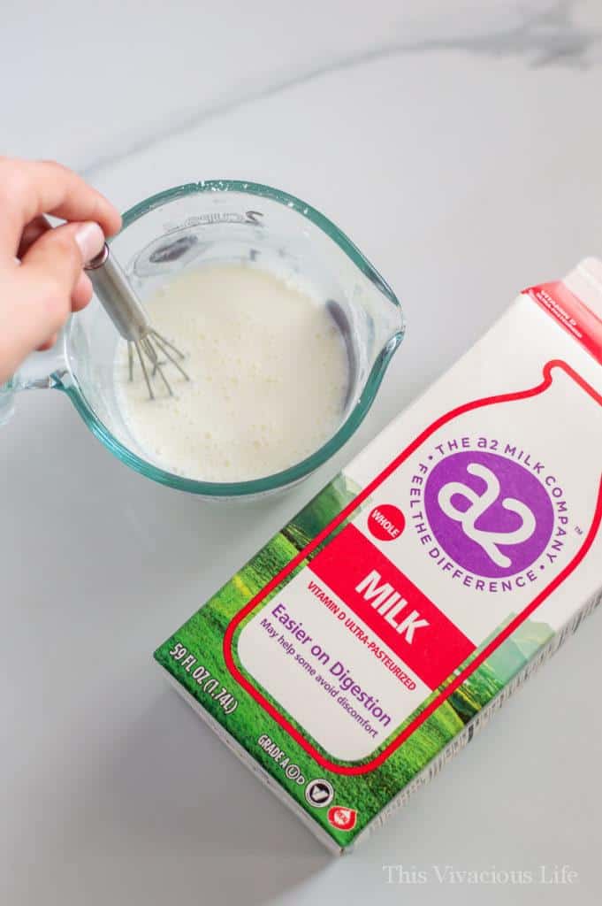Mixing cup whisking milk and cornstarch, carton of milk