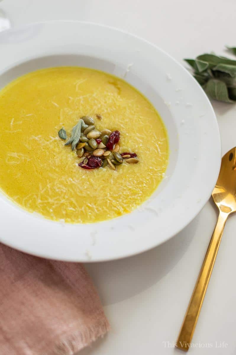 Cream of chicken soup in a white bowl with seeds and cranberries