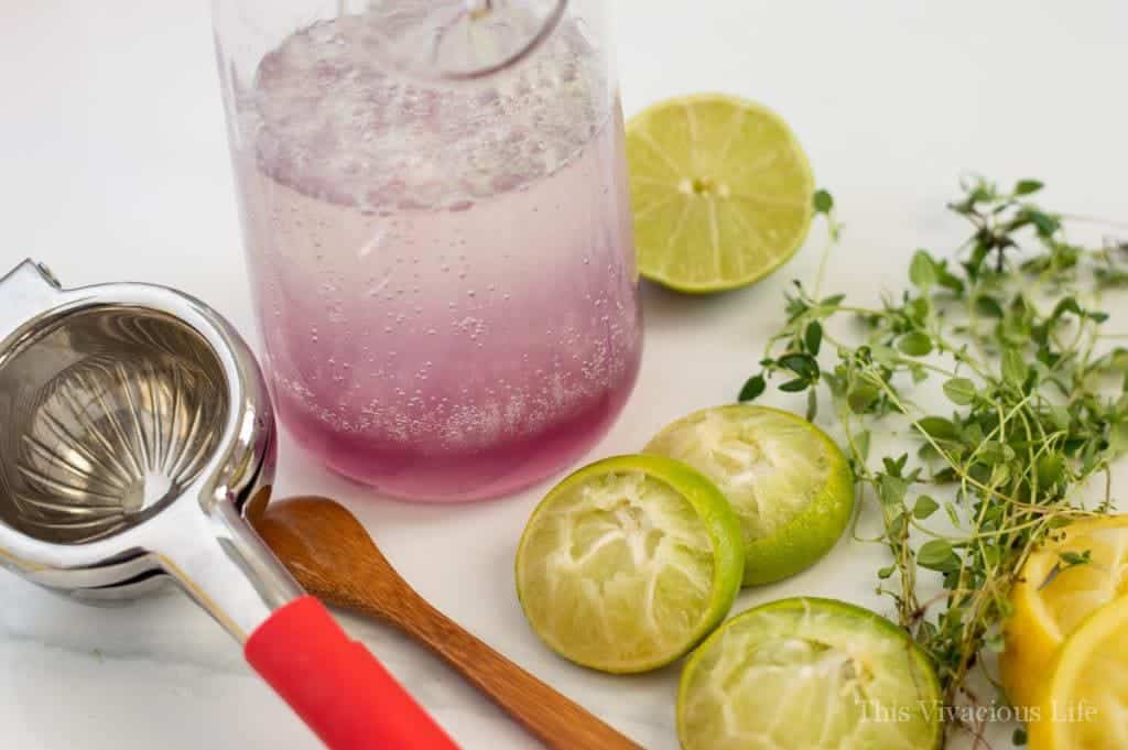 Slices of limes next to a glass pitcher with lavender limeade