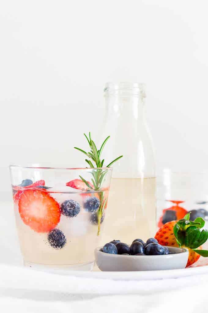 Tall pitcher and glass of ginger beer mocktail with berries