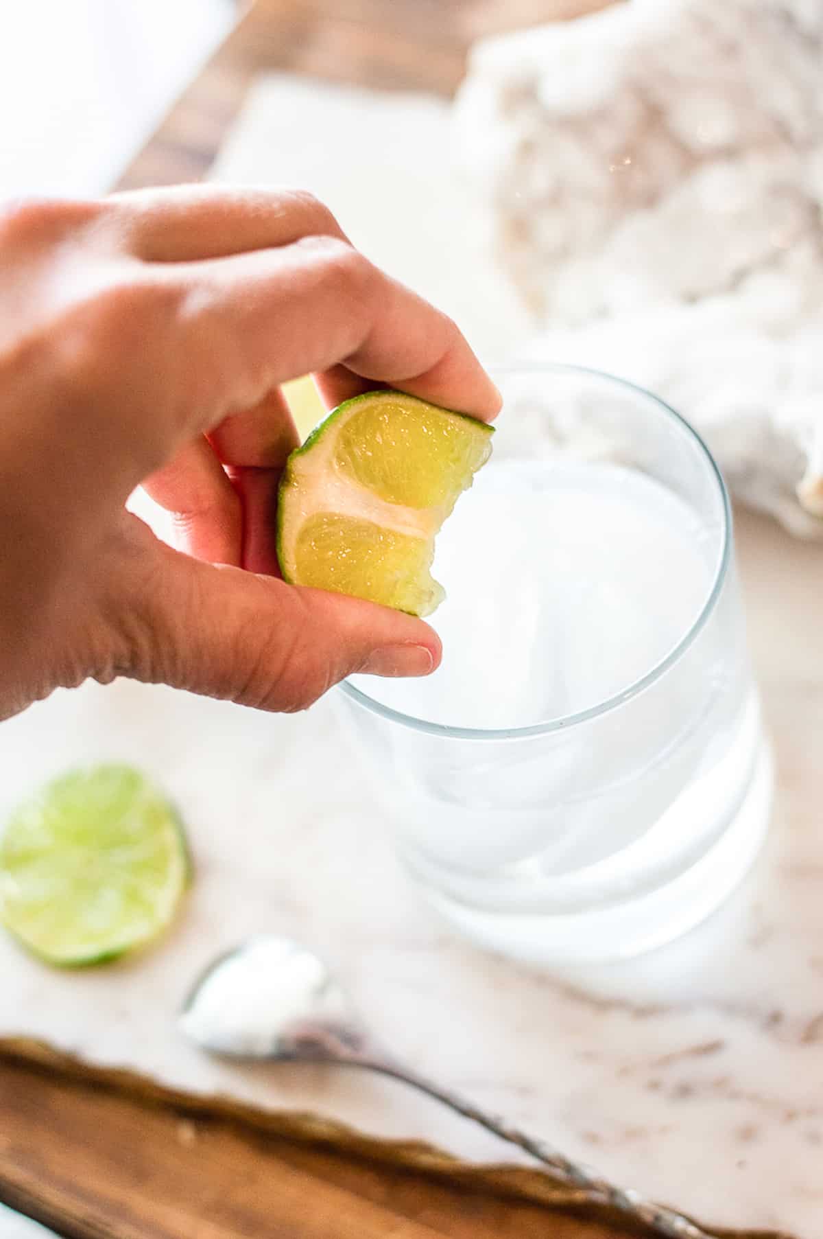 Lime being squeezed into a virgin gin and tonic