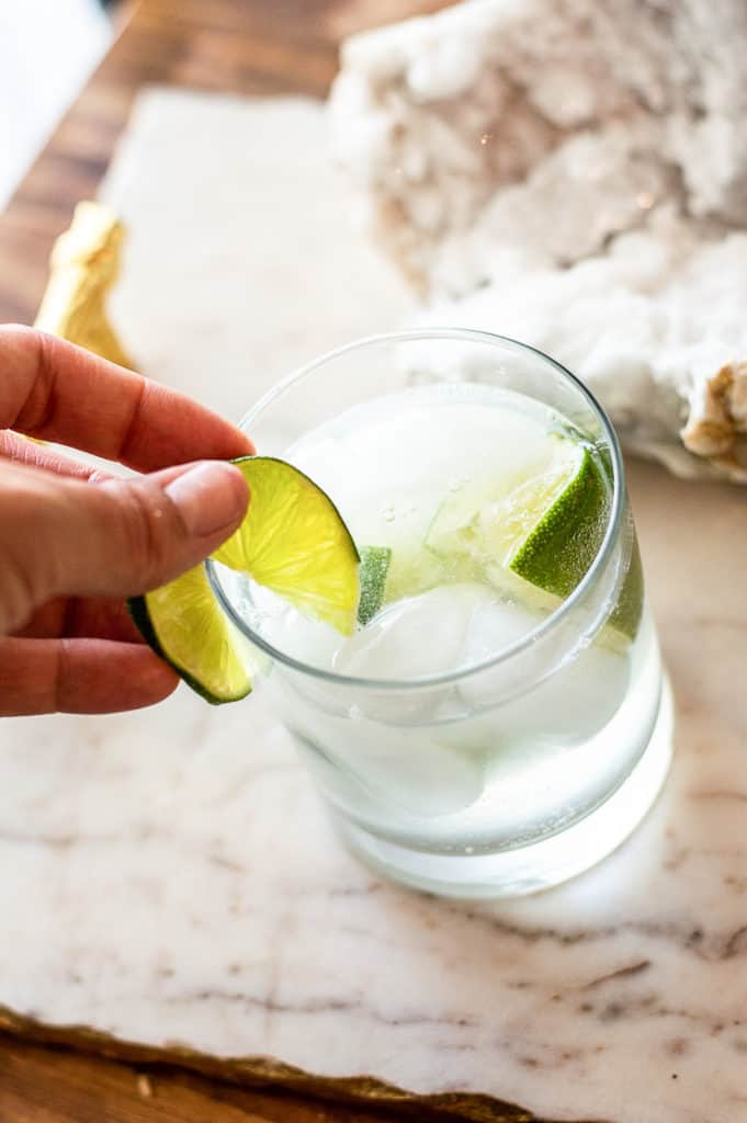 Lime being garnished on a non-alcoholic gin and tonic
