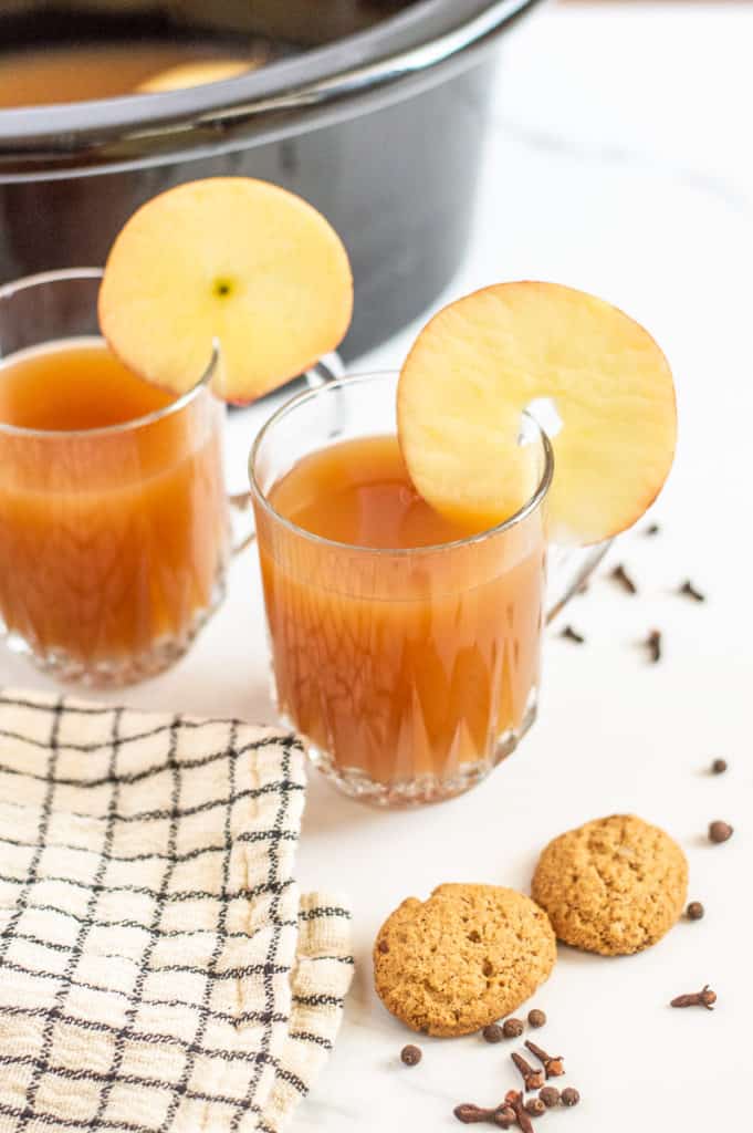 Crockpot apple cider in glass cups with apple slices 