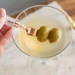 Non Alcoholic Dirty Martini Mocktail in a martini glass with olives