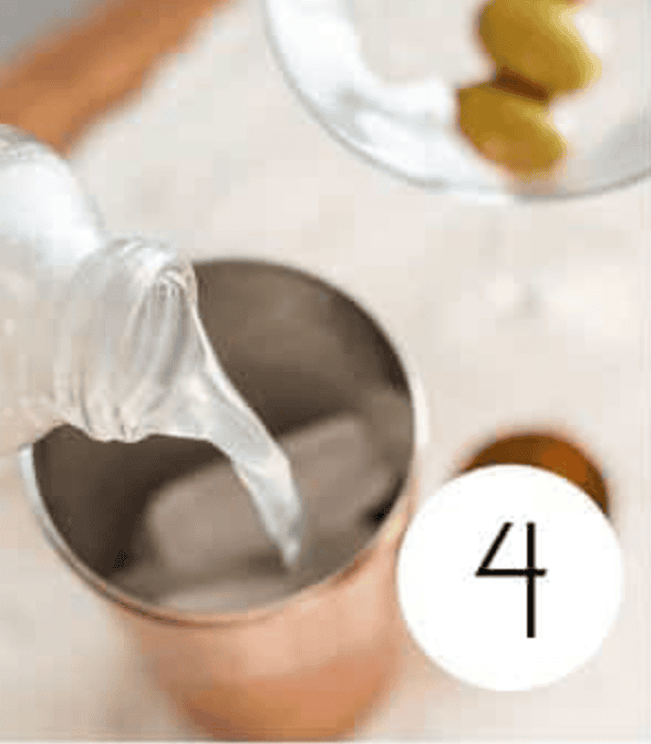 Non Alcoholic Dirty Martini Mocktail being poured in a copper shaker cup