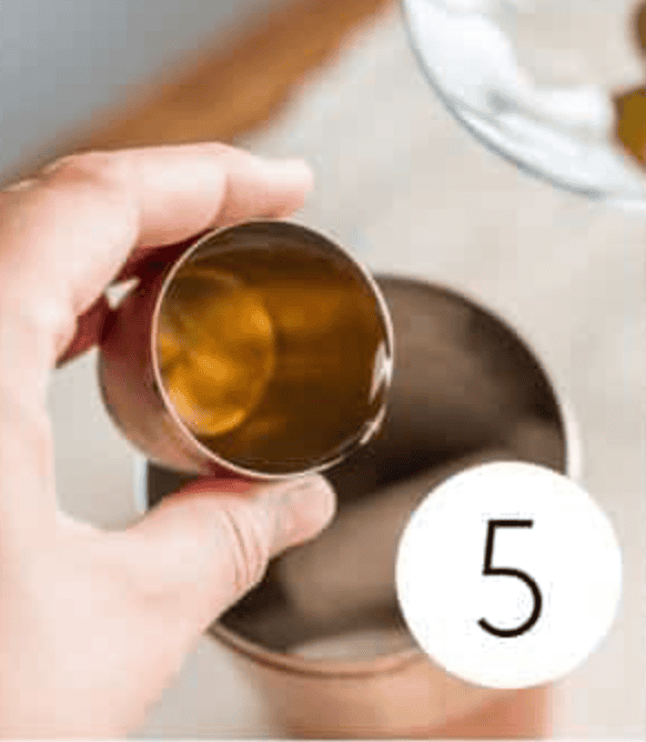 Non Alcoholic Dirty Martini Mocktail being shaken in a copper shaker cup