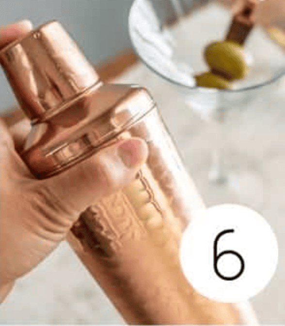 Non Alcoholic Dirty Martini Mocktail being shaken in a copper shaker cup