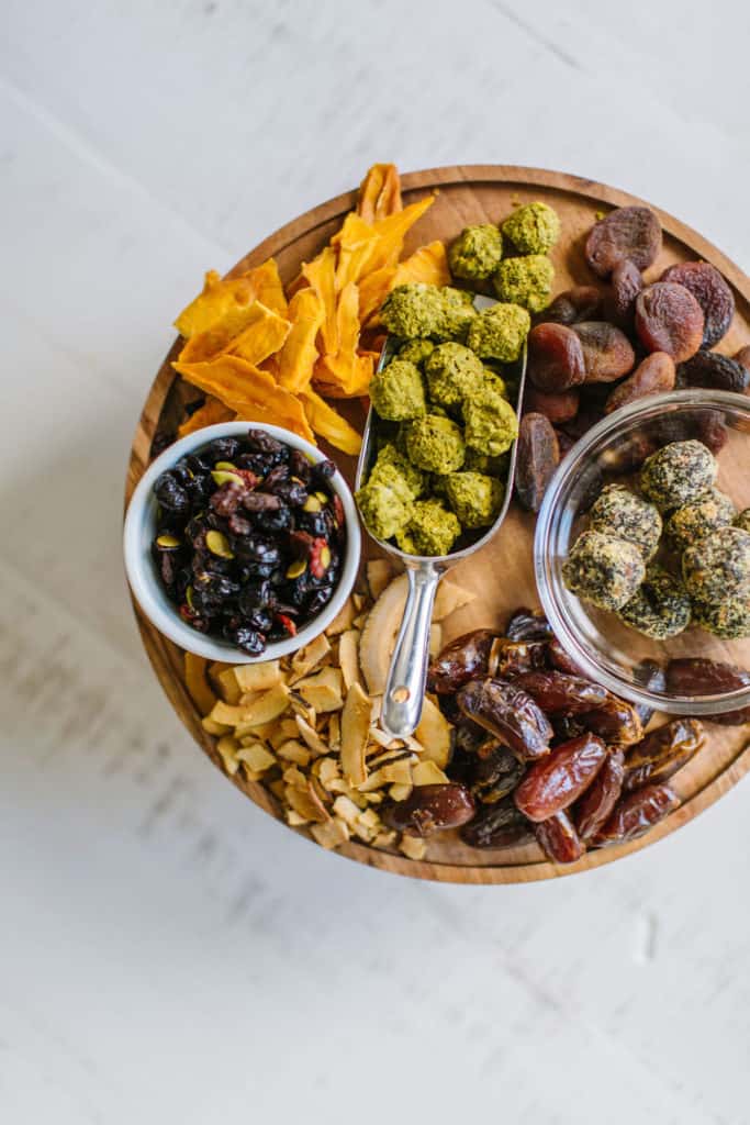 Round wood board with dried fruit, coconut chips and healthy snacks